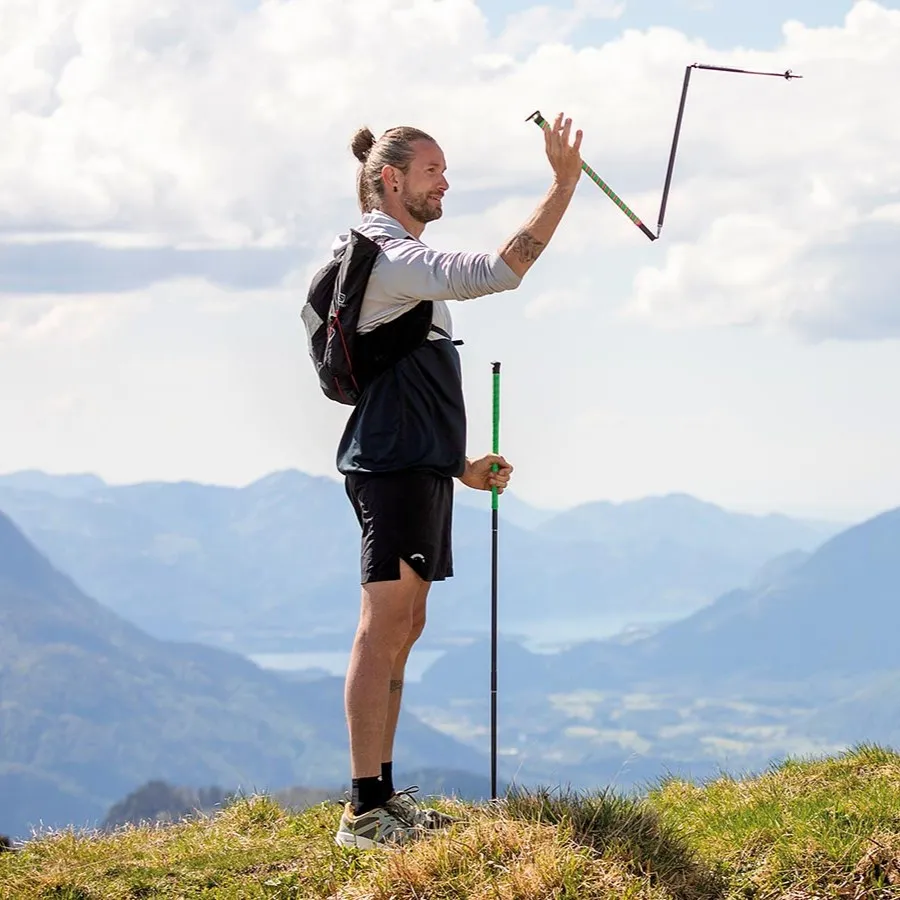 Excursionista con montañas al fondo y desplegando un bastón Komperdell