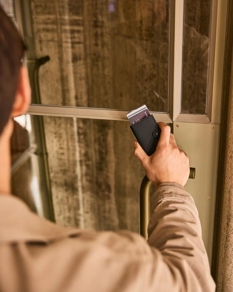 Chico sosteniendo una cartera Secrid Negra con el fondo en madera