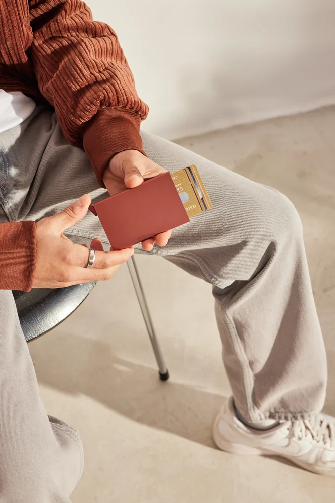 Chico sentado con pantalón beige y chaqueta naranja con cardprotector naranja.