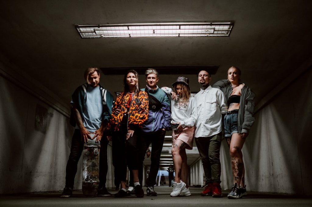 Sobre Nosotros Fashionable group of six adults posing stylishly in an urban underground setting.