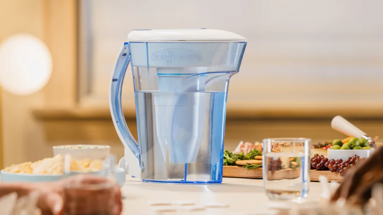 Mesa con un sanwich y una jarra Zerowater y un vaso.