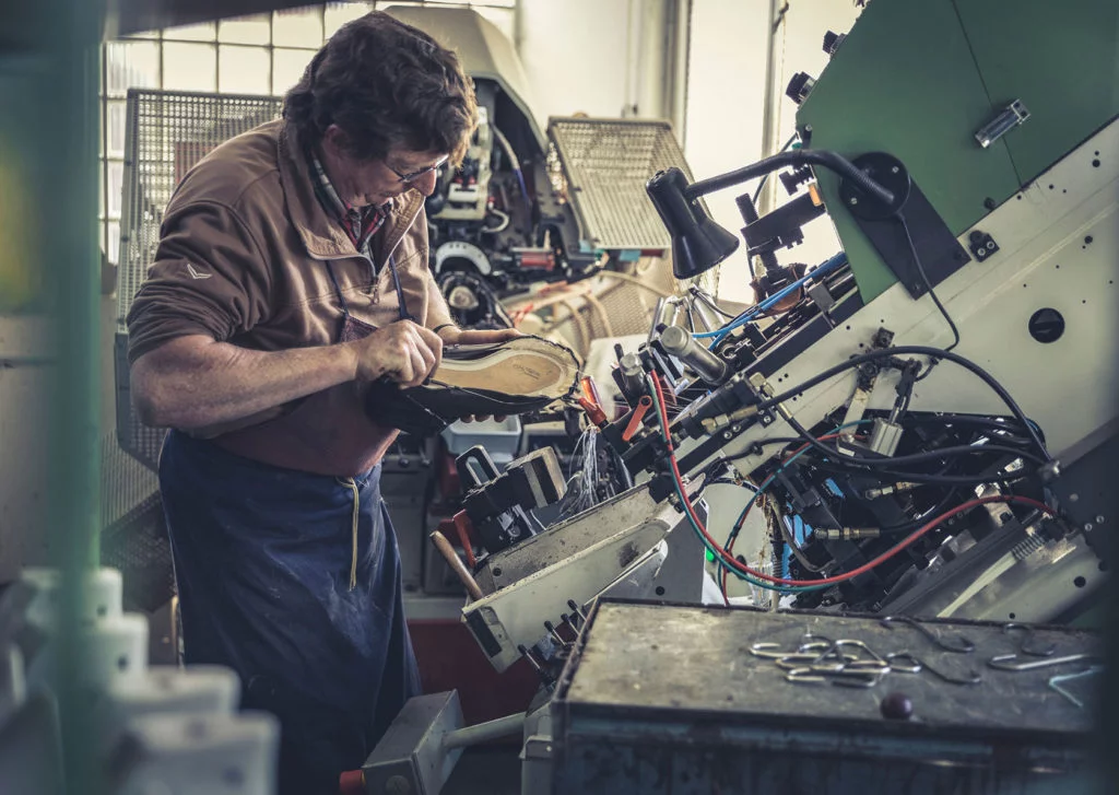 Zapatero construyendo una bota Hanwag en un maquina.