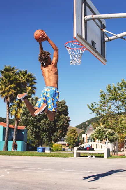 Moda Urbana Shirtless man performing a basketball dunk at outdoor court in summer.